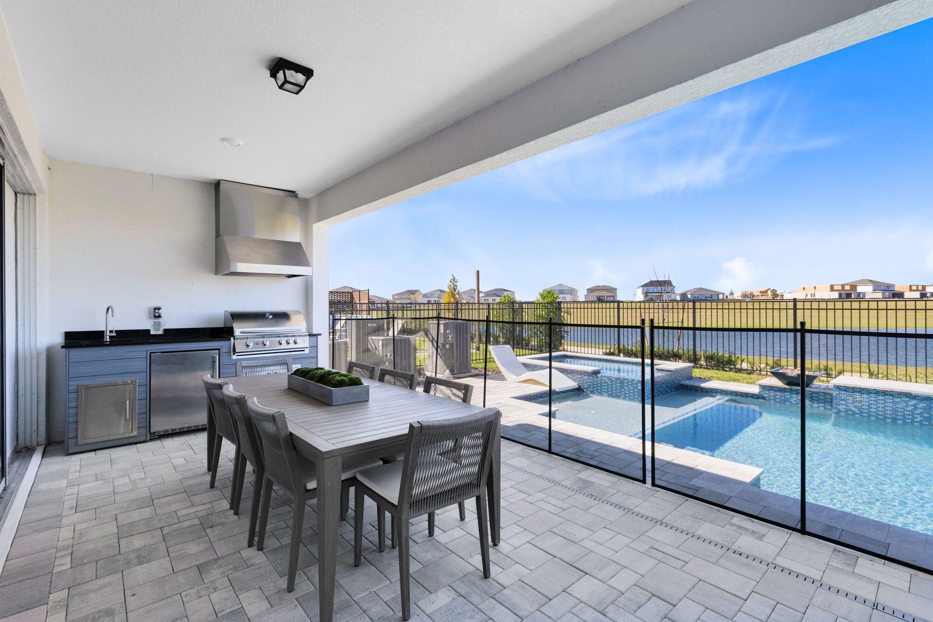 Covered lanai with outdoor kitchen overlooking a pool